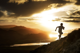 man running uphill outside with sunset behind him and water. Ross Woodhall - Action & Lifestyle Photography