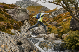Hiker jumping over a stream on a hill side Ross Woodhall - Action & Lifestyle Photography